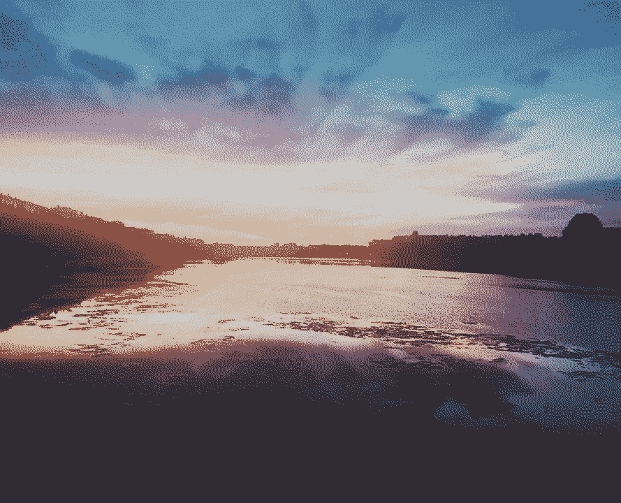 The beautiful Copenhagen summer sun setting over a body of water.