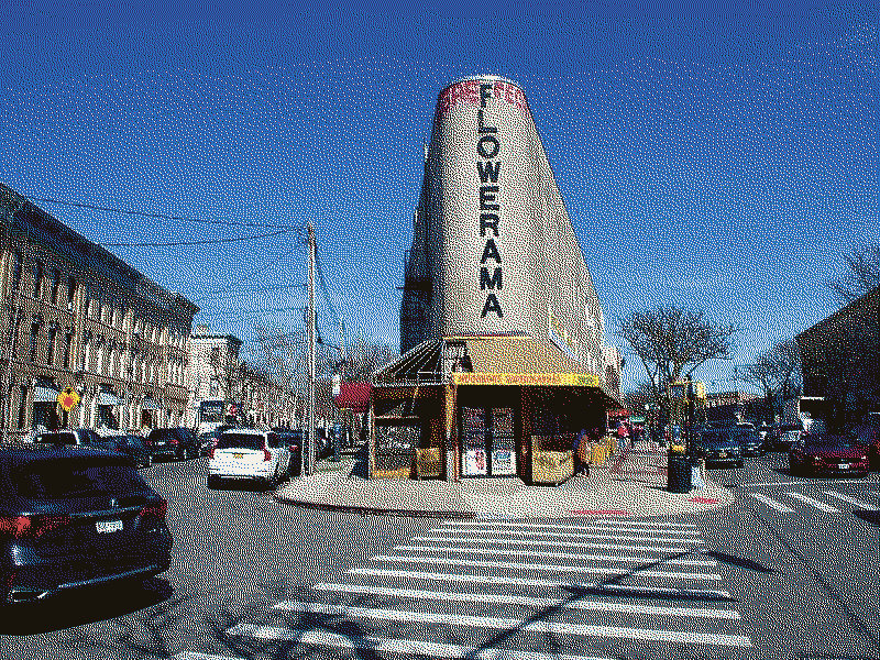 A flatiron-shaped building with a flowershop's name written down its face.